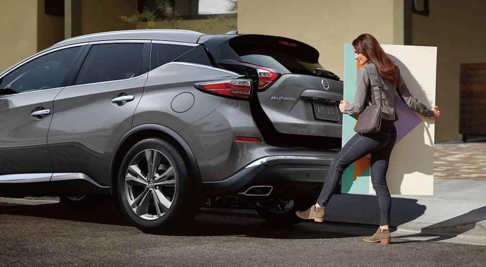 A woman is shown opening the liftgate in a grey 2023 Nissan Murano.