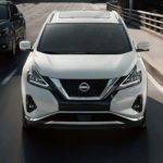 A white 2023 Nissan Murano is shown from the front driving on a highway.