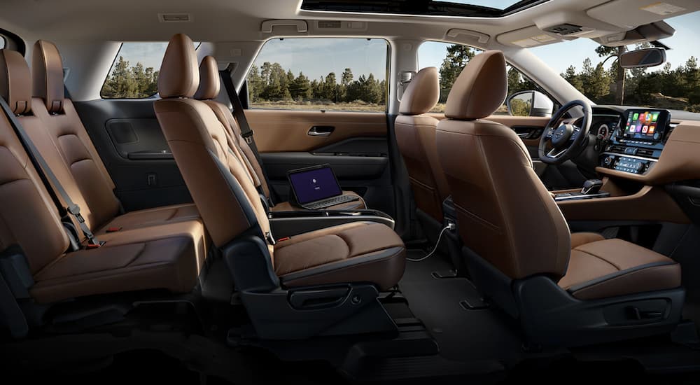 The brown interior of a 2023 Nissan Pathfinder shows three rows of seating.