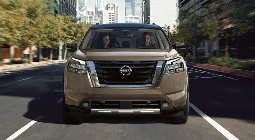 A brown 2023 Nissan Pathfinder is shown from the front driving on an open road.