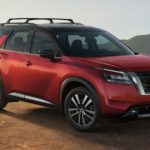 A red 2023 Nissan Pathfinder for sale, is shown from the side parked in the mountains.