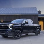 A black 2023 Chevy Silverado 2500 HD is shown from the front at an angle while parked in front of a house.