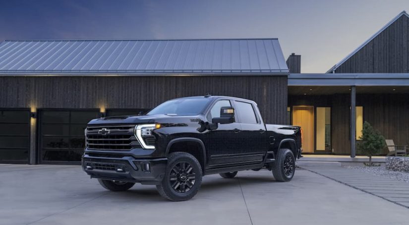 A black 2023 Chevy Silverado 2500 HD is shown from the front at an angle while parked in front of a house.