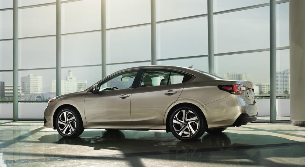 A tan 2023 Subaru Legacy is shown from the rear at an angle.