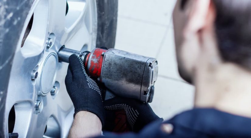A person is shown using an impact wrench to remove lug nuts.
