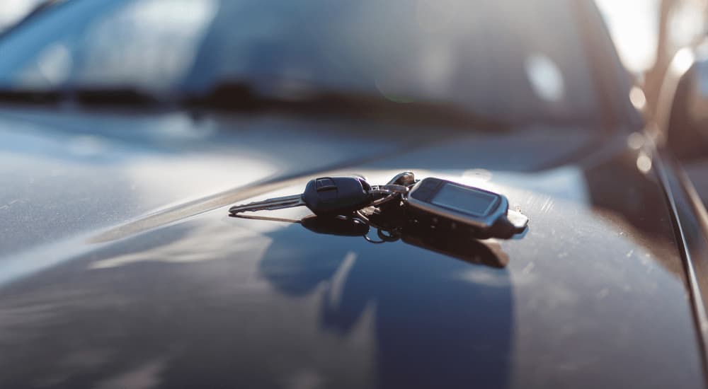 A set of car keys is shown on a black vehicle's hood.