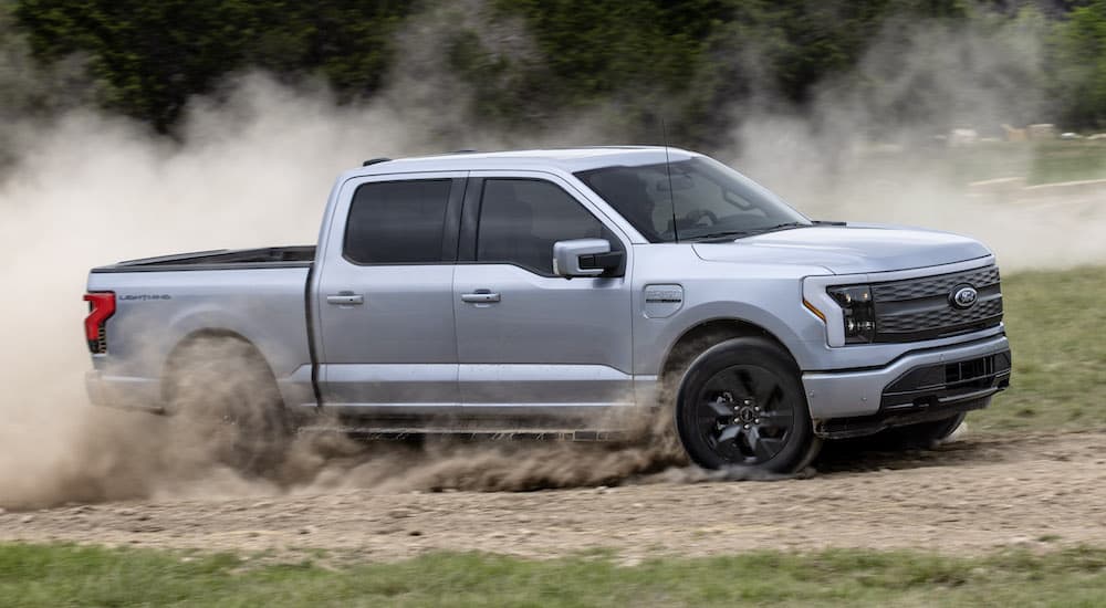 a silver 2022 Ford F-150 Lightning Lariat is shown from the side while driving off-road after leaving a used Ford dealer.