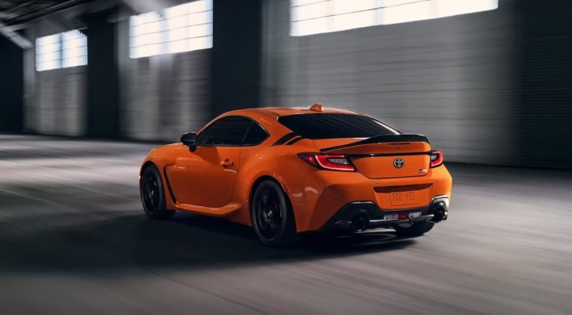 An orange 2023 Toyota GR86 10th Anniversary Edition is shown from the rear at an angle.