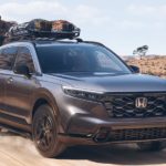 A grey 2023 Honda CR-V Sport Hybrid is shown driving on a dirt road.