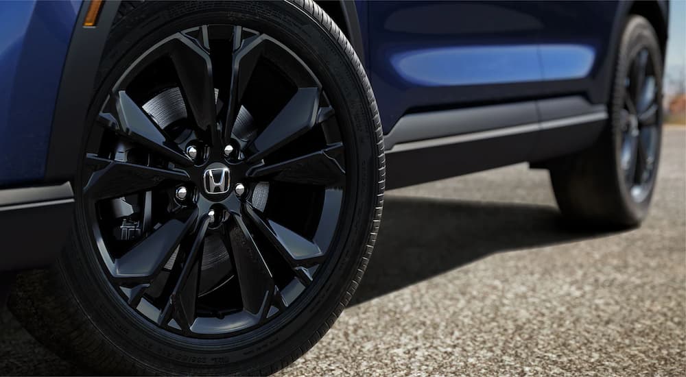 A close up shows the black wheels on a blue 2023 Honda CR-V Hybrid Sport Touring.