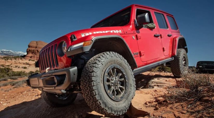 A red 2023 Jeep Wrangler Rubicon 392 is shown from the front while driving in a rocky area.