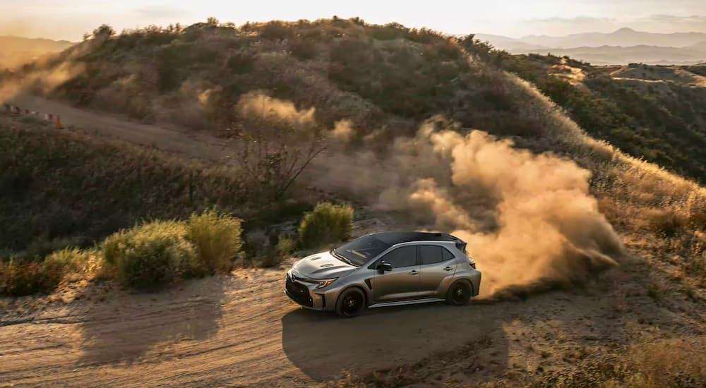 A silver 2023 Toyota GR Corolla is shown kicking up dust after leaving a Toyota dealer.