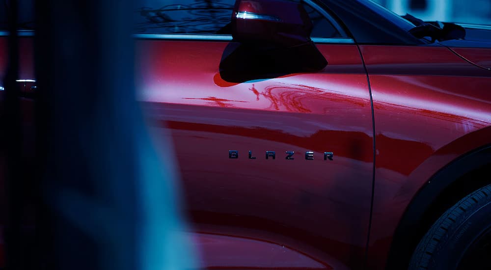A close up shows the Blazer badge on the passenger side door of a red 2019 Chevy Blazer RS.