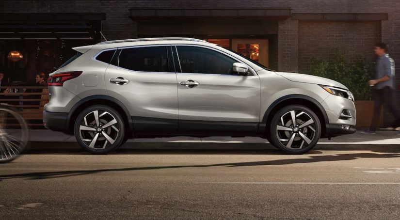 A silver 2022 Nissan Qashqai is shown from the side parked on a city street.