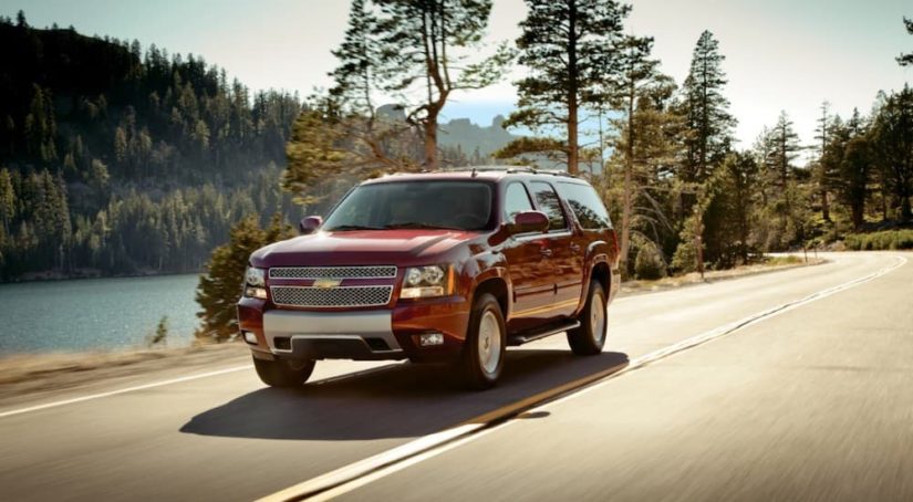 A red 2014 Chevy Suburban is shown driving on an open road after viewing used cars for sale.