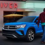 A man is shown walking towards the driver's side of a blue 2022 Volkswagen Taos.