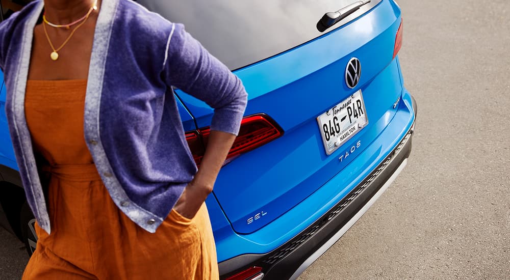 A person is shown walking past the rear of a blue 2022 Volkswagen Taos.