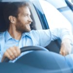 A man is shown sitting in the driver's seat of a vehicle as he looks out of the window.