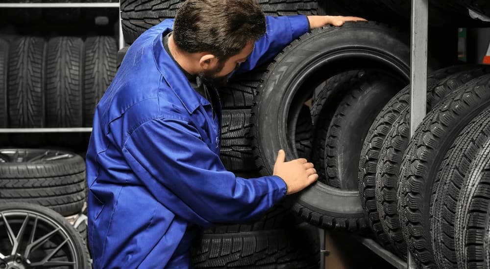 A mechanic is shown inspecting a winter tire in a storage room.