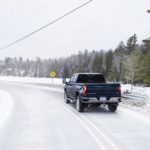 A blue 2020 Chevy Silverado 2500HD is shown from the rear on a snow covered road.