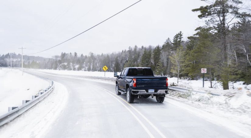 A blue 2020 Chevy Silverado 2500HD is shown from the rear on a snow covered road.