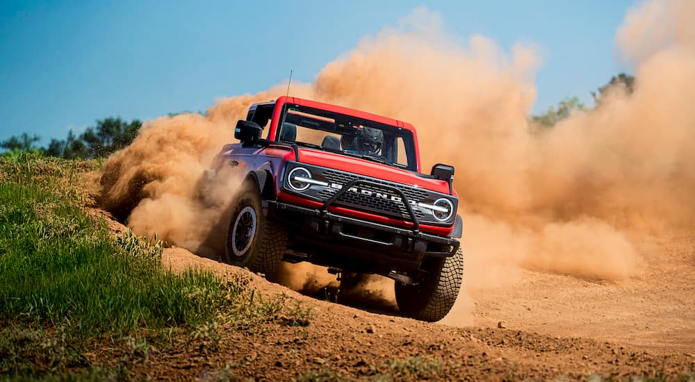 A red 2023 Ford Bronco Wildtrak is shown from the front while driving off-road.