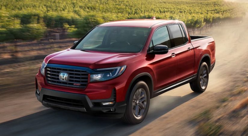 A red 2022 Honda Ridgeline is shown from the front at an angle on a dirt road.