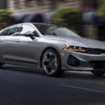 A grey 2021 Kia K5 is shown from the front at an angle.