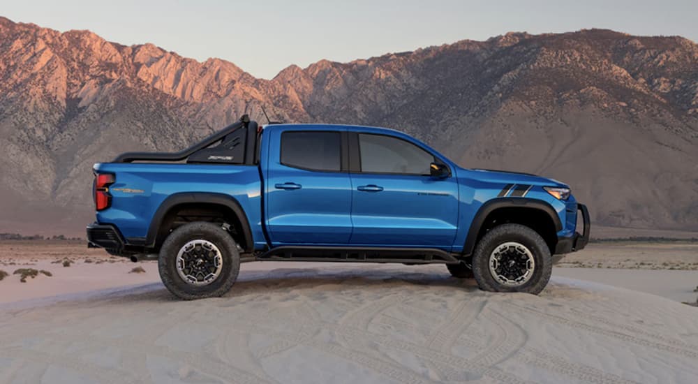 A blue 2023 Chevy Colorado ZR2 is shown from the side parked on a beach during a 2023 Chevy Colorado vs 2023 Toyota Tacoma comparison.