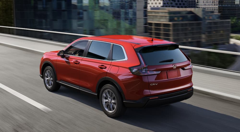 A red 2023 Honda CR-V EX is shown from the rear driving on an open road.