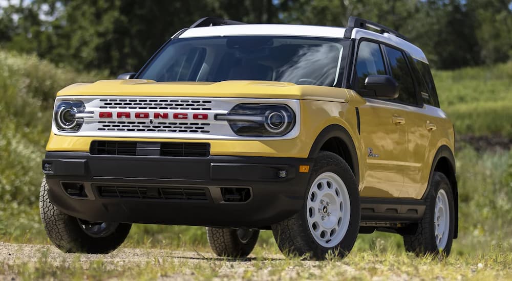 A yellow 2023 Ford Bronco Sport Heritage Limited is shown parked on a dirt path through a grassy field.