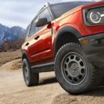 A close up of a red 2023 Ford Bronco Sport driving on a dirt road is shown.