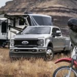 A silver 2023 Ford F-450 is shown parked at a remote campsite.