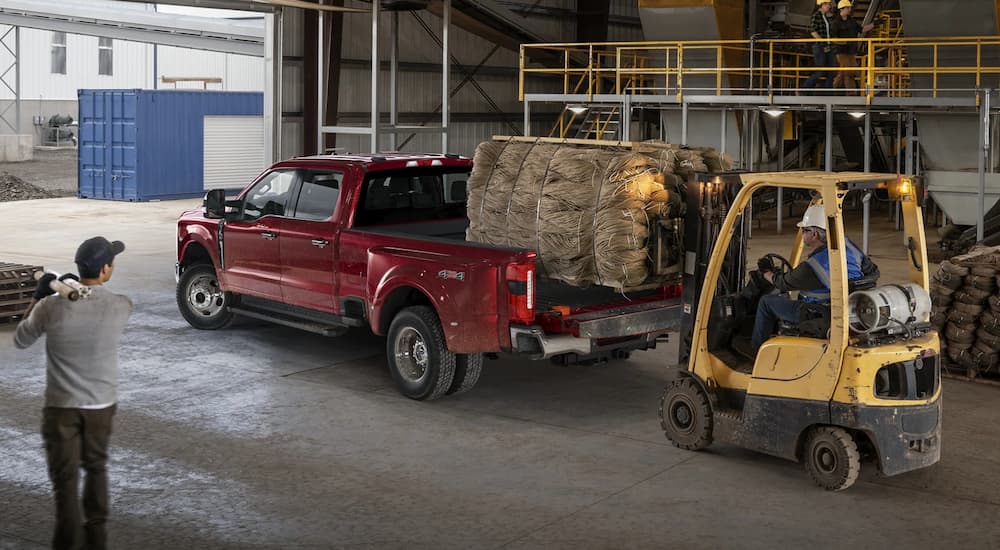 A forklift is shown loading cargo into the bed of a red 2023 Ford F-450.