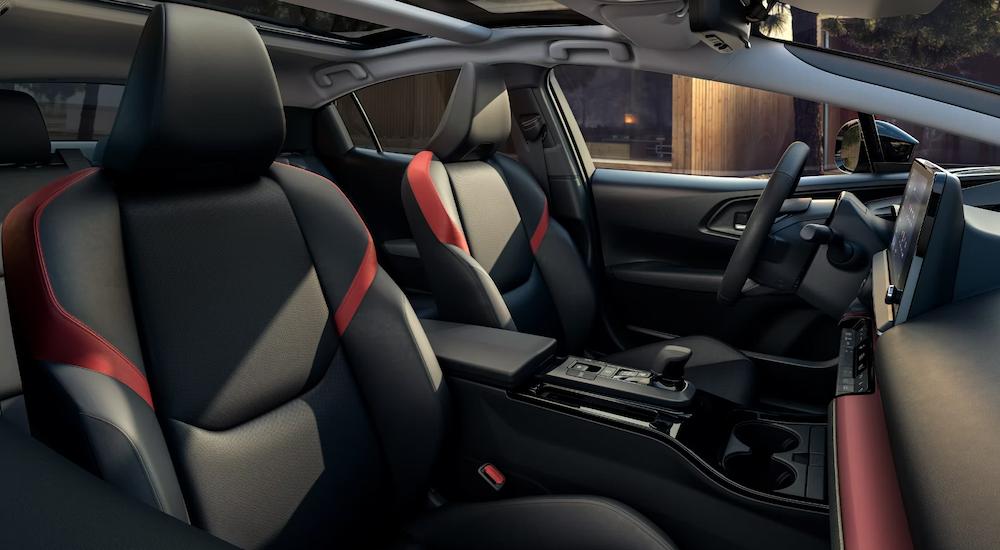 The black and red interior of a 2023 Toyota Prius Prime shows the two front seats and center console.