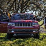 A red 2023 Wagoneer is shown from the front parked in an apple orchard.