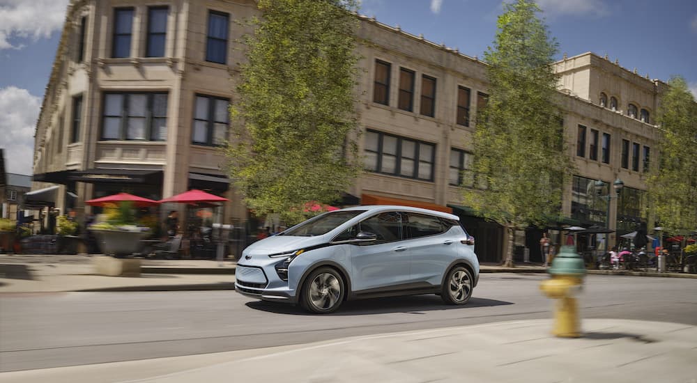A blue 2024 Chevy Bolt EV is shown from the side.