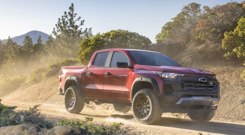 A red 2023 Chevy Colorado Trail Boss is shown from the front at an angle after leaving a dealer that has a Chevy Colorado for sale.