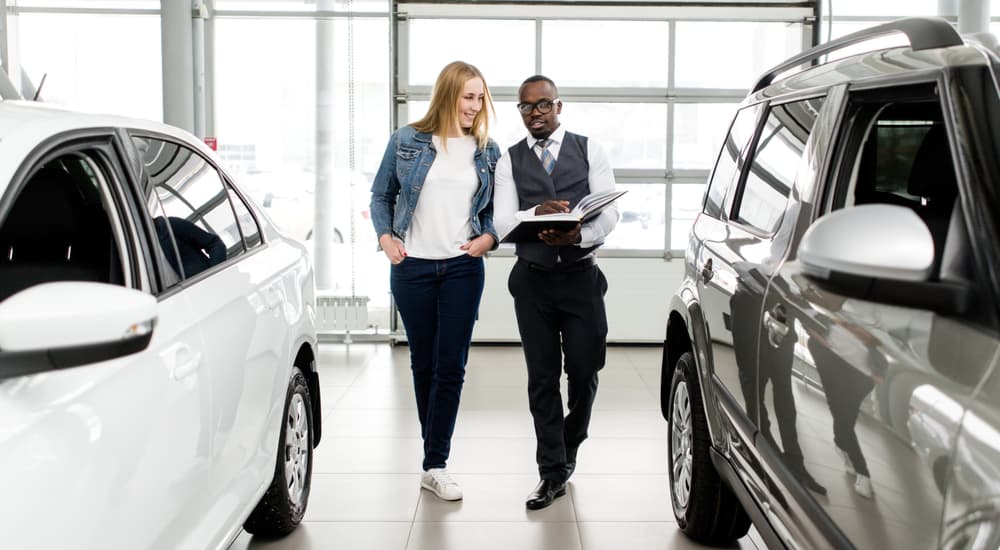 A car salesman is shown speaking to a customer at a dealership.