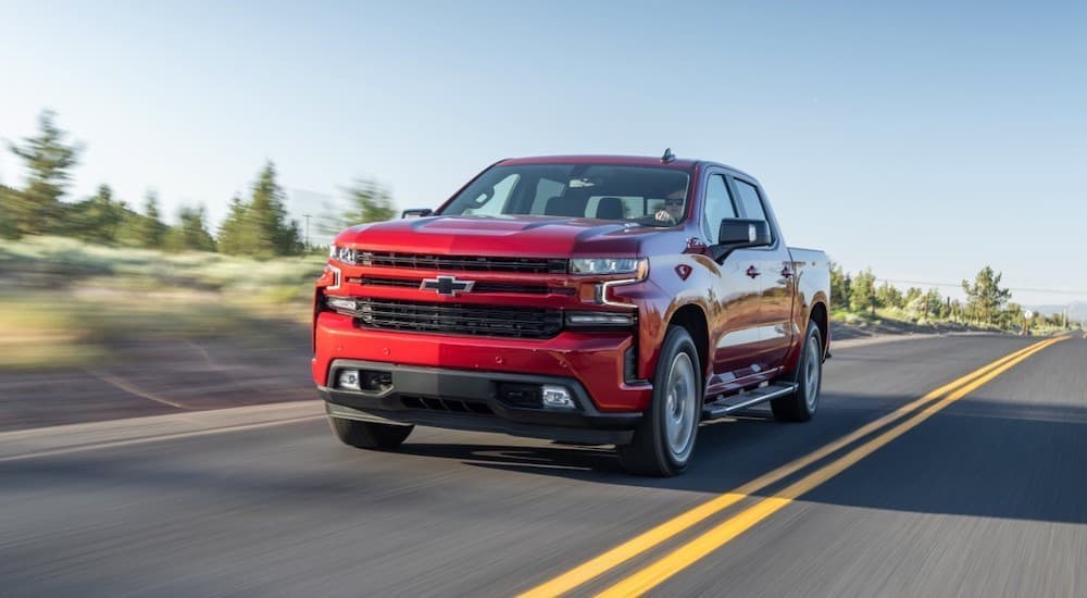 A popular Certified Pre-Owned Chevy Silverado, a red 2020 Chevy Silverado 1500 is shown driving on an open road.