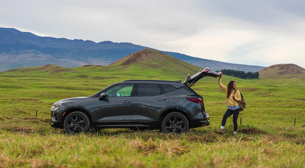 A hiker is shown opening the liftgate on a black 2020 Chevy Blazer RS.