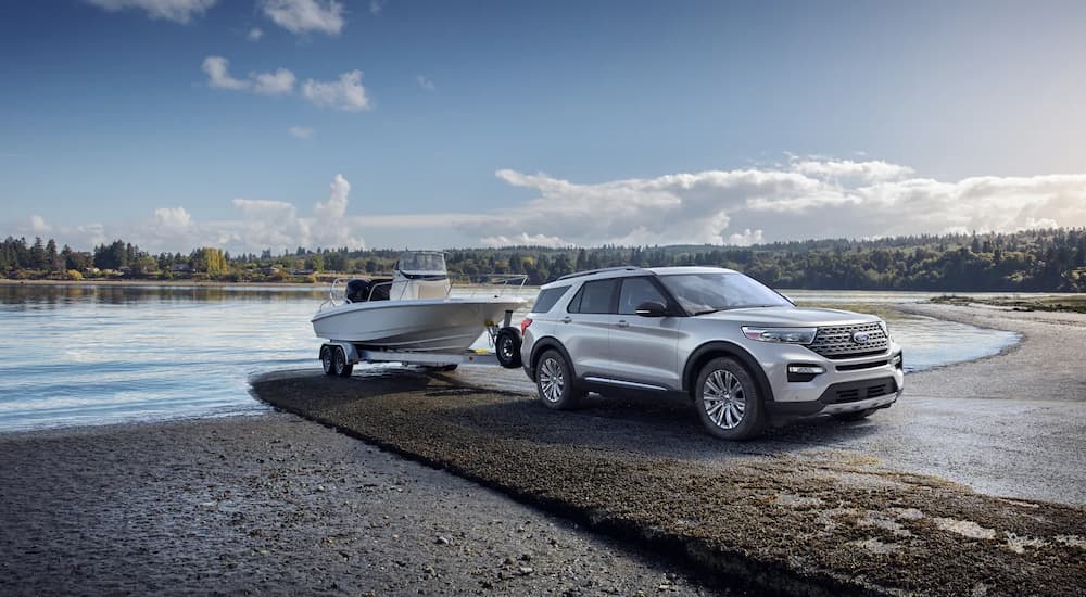 A silver 2023 Ford Explorer Platinum is shown towing a small fishing boat out of a lake.