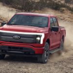 A red 2023 Ford F-150 Lightning is shown off-roading.
