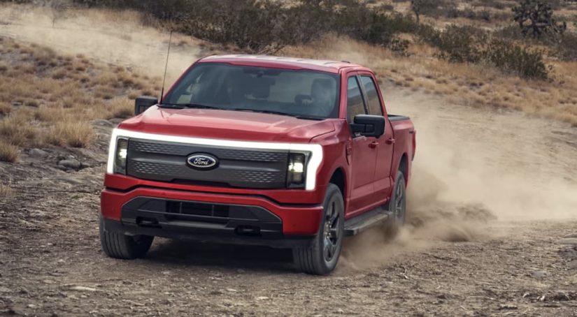 A red 2023 Ford F-150 Lightning is shown off-roading.