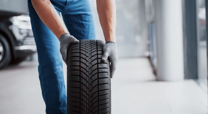 A mechanic is shown rolling a tire through a tire center.