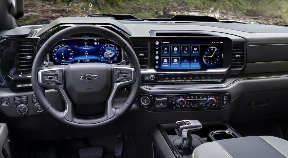 The black interior of a 2023 Chevy Silverado 1500 shows the steering wheel and infotainment screen.