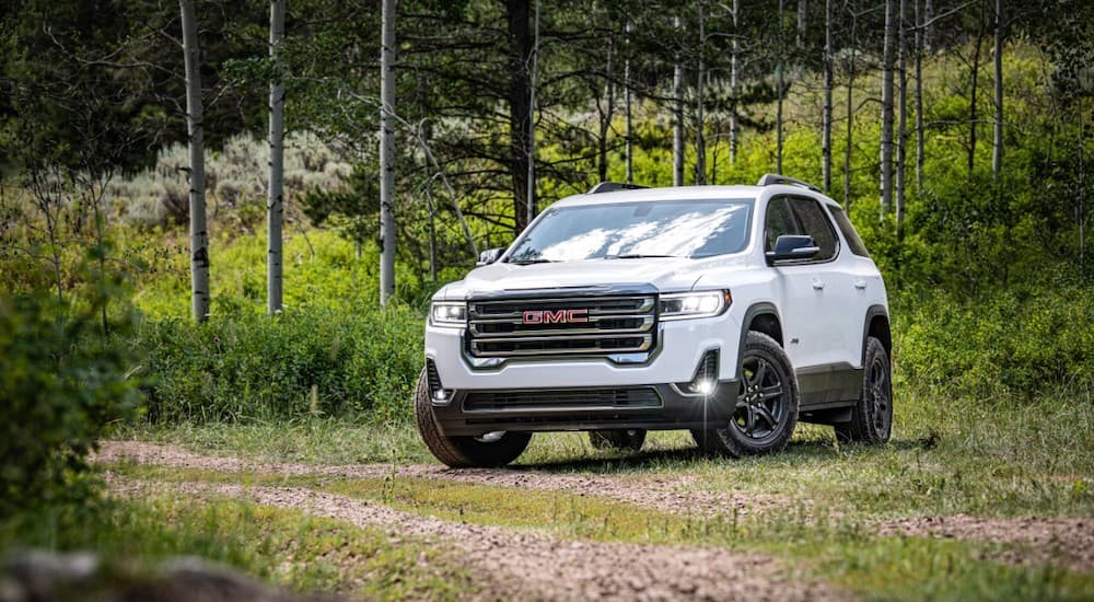 A white 2020 GMC Acadia is shown from the front at an angle while parked off-road.