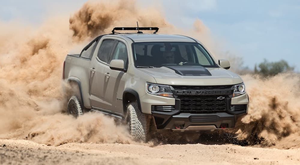 A tan 2021 Chevy Silverado ZR2 is shown from the front while driving through sand after leaving a dealer that has used trucks for sale.