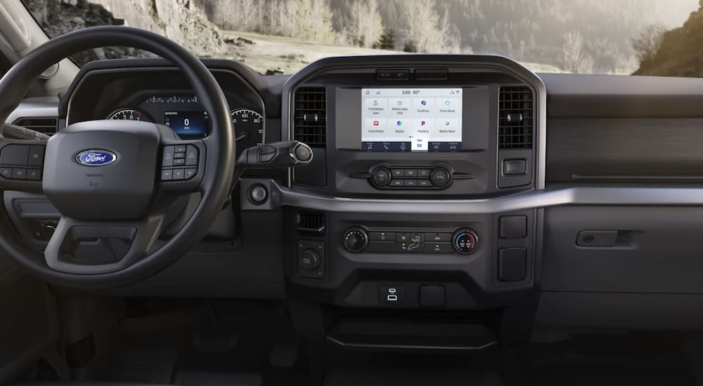 The black interior of a 2023 Ford F-150 shows the steering wheel and infotainment screen.