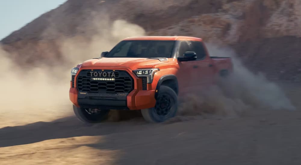 An orange 2023 Toyota Tundra TRD is shown off-roading.